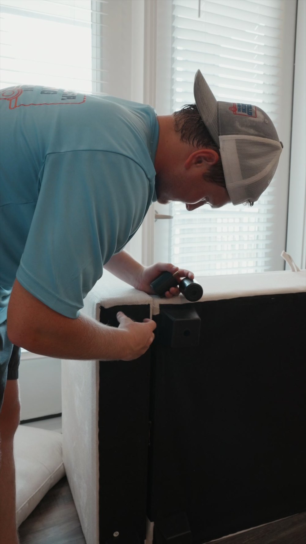 A McCuller Moving crew member using a drill to assemble a new sofa in a student apartment